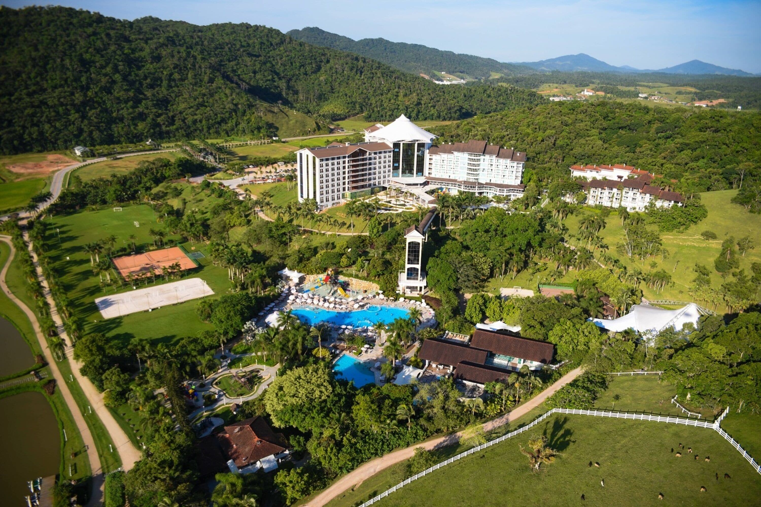 A resort with a large pool, multiple buildings, and surrounding greenery.