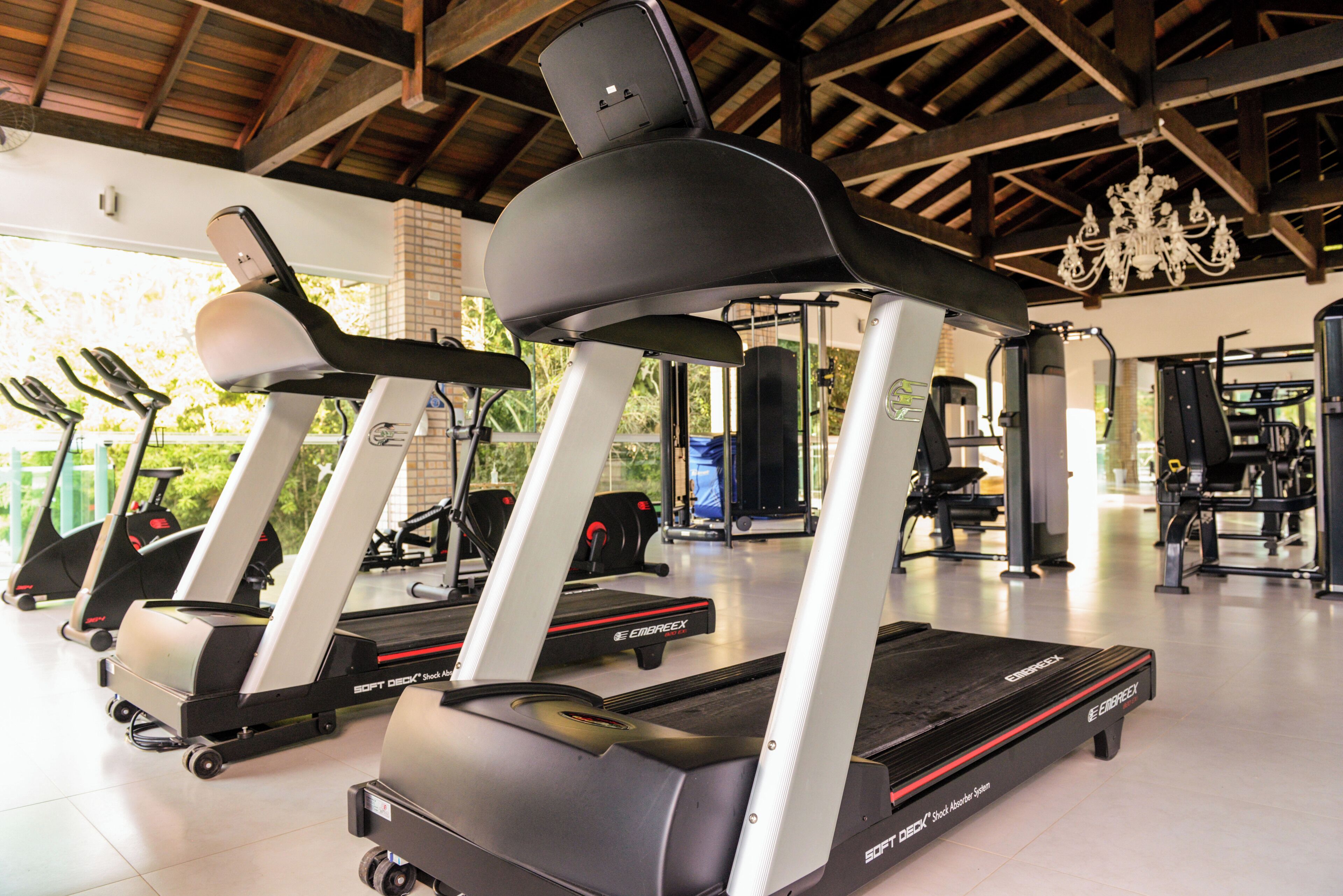 Un gimnasio con cintas de correr, máquinas de pesas y un candelabro.
