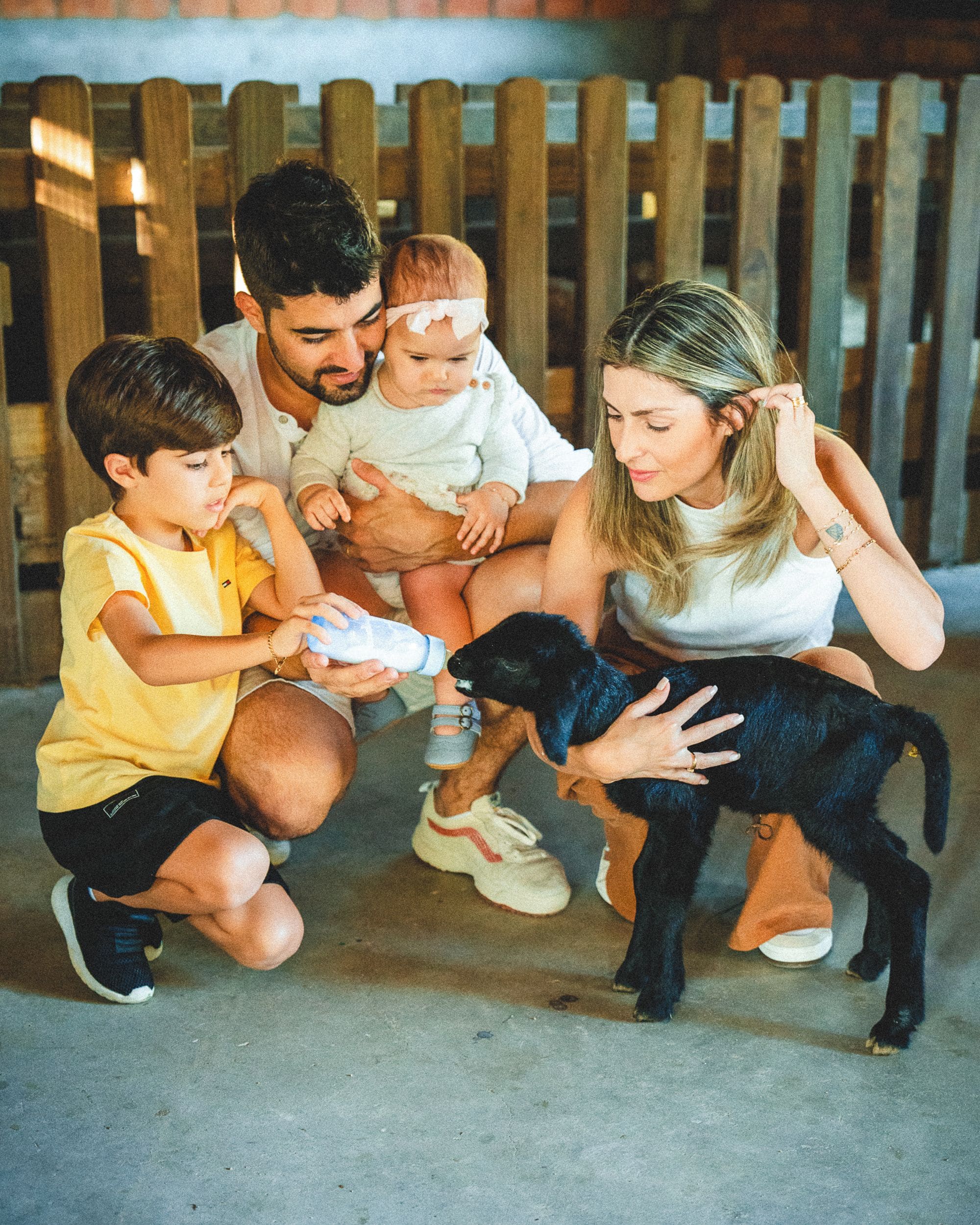 Una familia con un cachorro en un espacio al aire libre cubierto, con una valla de madera.