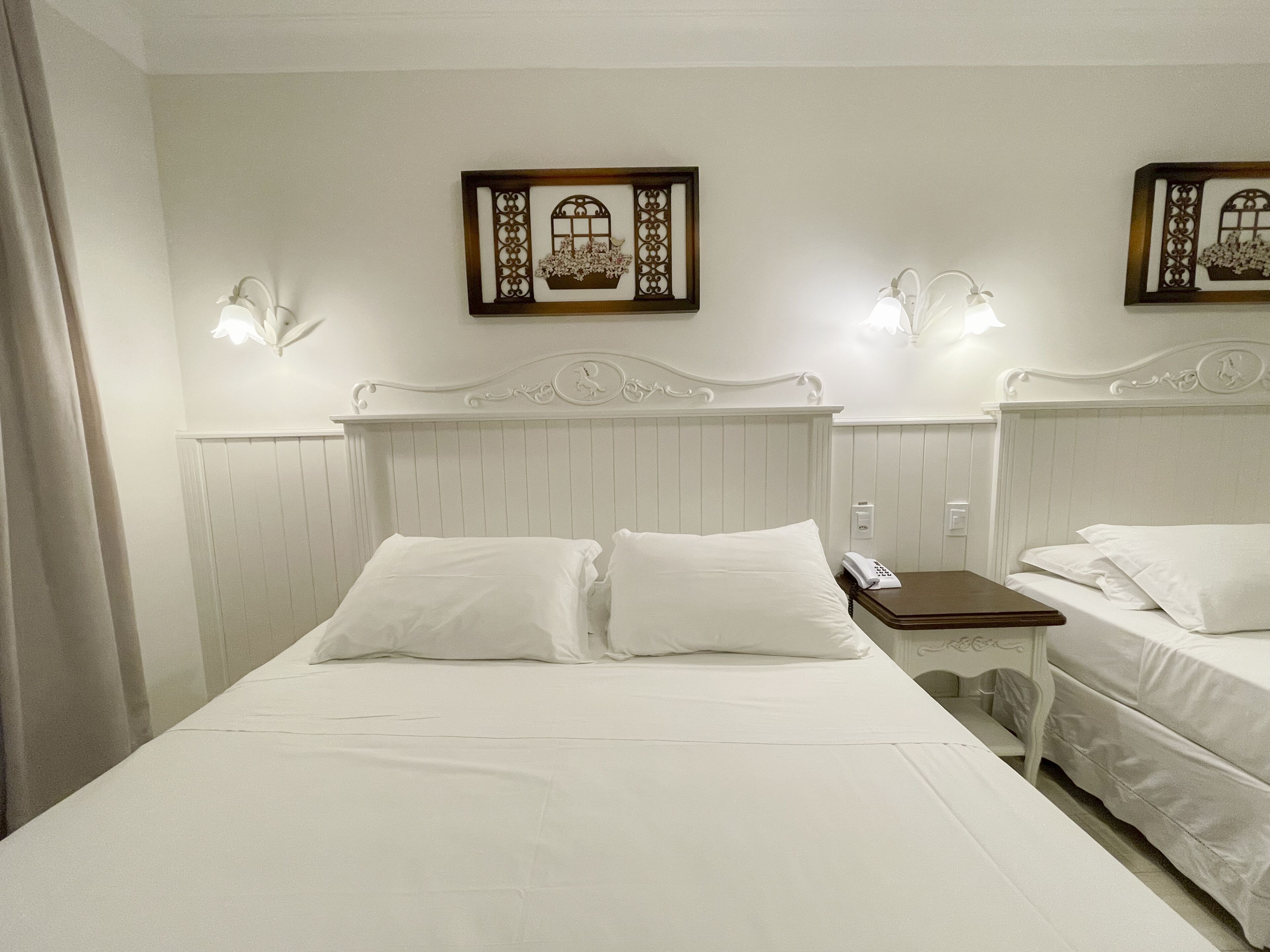 A hotel room with a large bed, two bedside tables, and two wall-mounted lamps.