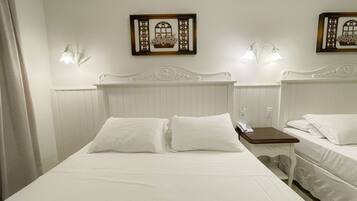 A hotel room with a large bed, two bedside tables, and two wall-mounted lamps.