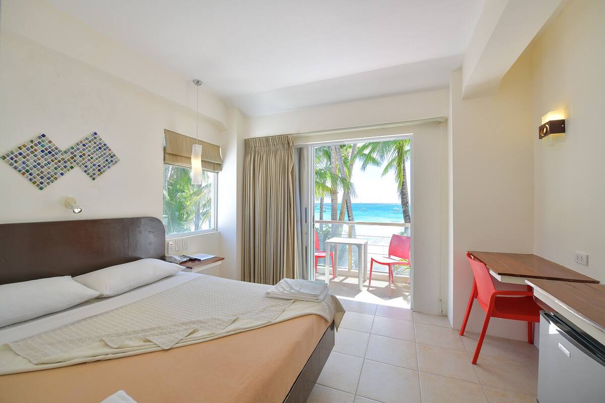 Une chambre d’hôtel avec un lit, un bureau et une vue sur la plage.