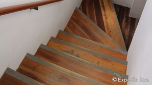 Una escalera de madera con barandilla, paredes blancas y una decoración de peces en la pared.