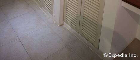 A hallway with two beige louvered closets and a wooden counter.