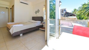 Habitación de hotel con una cama, una mesita de noche, una ventana y vistas a palmeras.