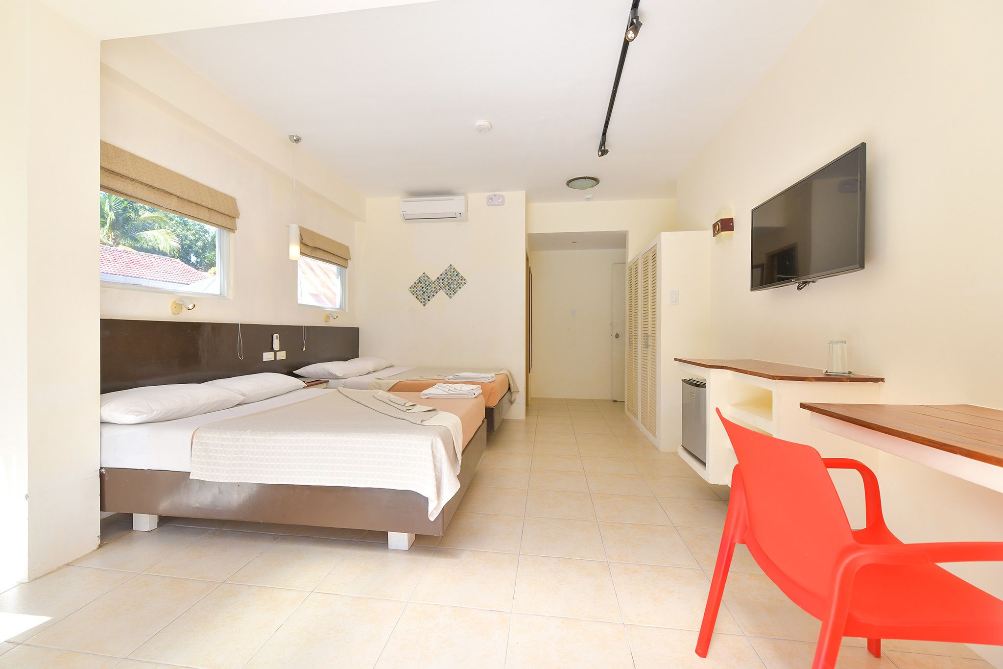 Una habitación de hotel con una cama, un escritorio, un televisor y una ventana.