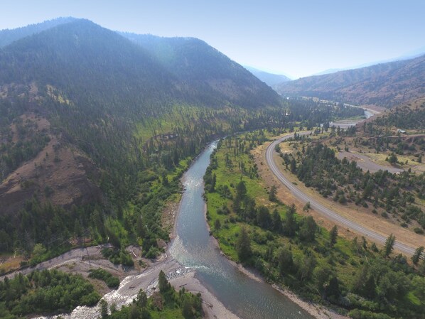 Une rivière serpente à travers un paysage montagneux, avec une route qui la longe en suivant ses méandres.