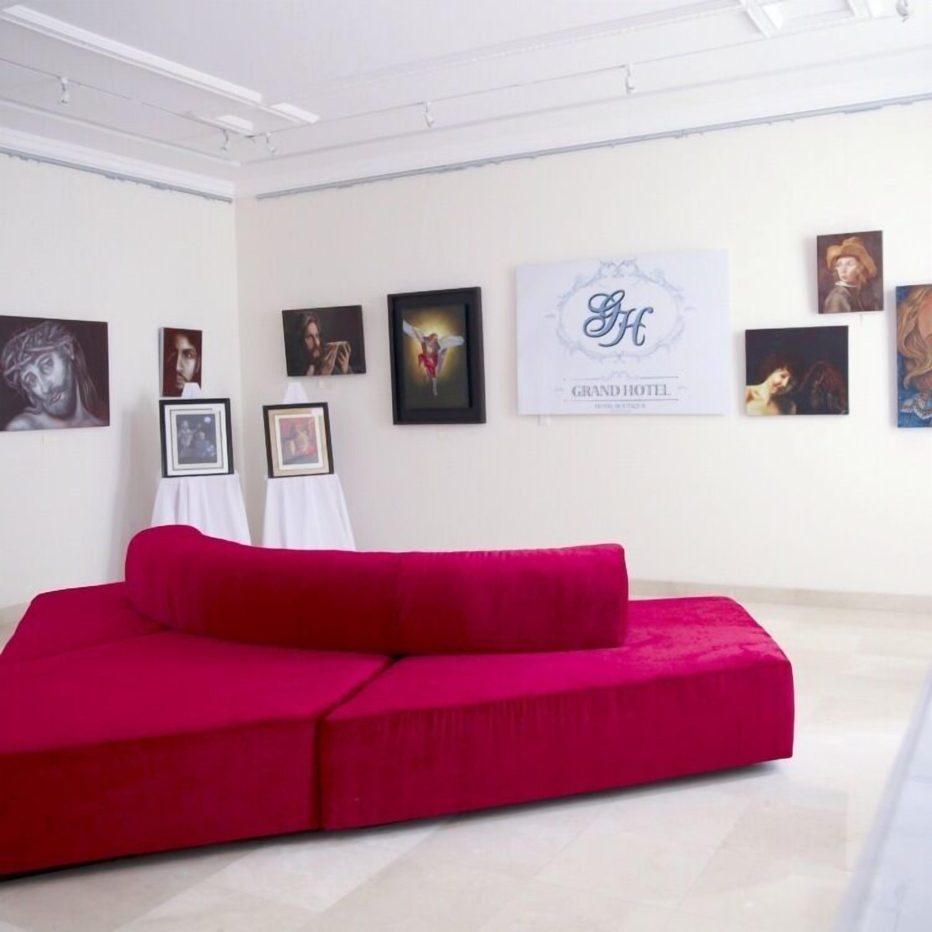 Una galería con obras de arte en las paredes, un sofá rojo y un cartel que dice "GRAND HOTEL".