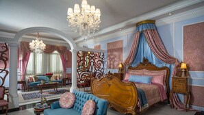Um quarto luxuoso com uma cama grande, cortinas ricamente decoradas e um candelabro.