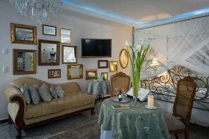 A cozy room with a sofa, a table with a candle, and a TV on the wall. - Grand Hotel, Hotel Boutique Tepatitlán (Tepatitlan de Morelos)