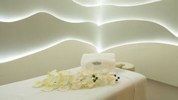 A spa area with a white reception desk, a towel, and white flowers.