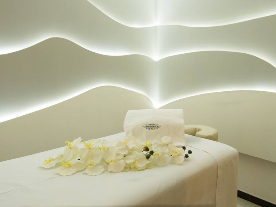 A spa area with a white reception desk, a towel, and white flowers.
