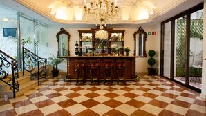 Uma área de bar com piso quadriculado, um candelabro e um balcão com banquetas.