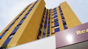 A tall building with a yellow facade and blue accents. - Astro Hotel (São José dos Campos)