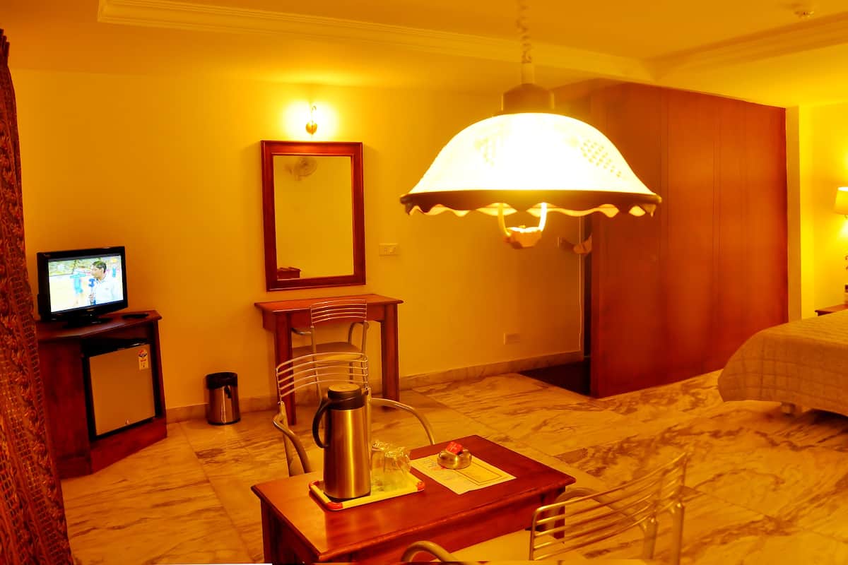 A hotel room with a bed, a desk with a lamp, a television, and a mirror.