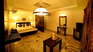 A hotel room with a bed, bedside table, lamp, TV, and a mirror. - Nayagara Hotel (Chennai)