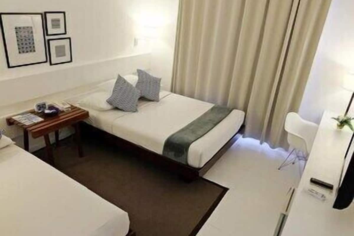 Una habitación de hotel con cama, mesita de noche, lámpara y una silla.
