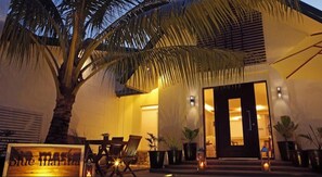 L’entrée d’un hôtel, avec un palmier, des sièges en plein air et des plantes en pot.