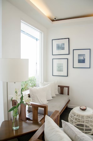 Una habitación moderna y luminosa con una cama, una silla, una mesa con un florero y cuadros en la pared.