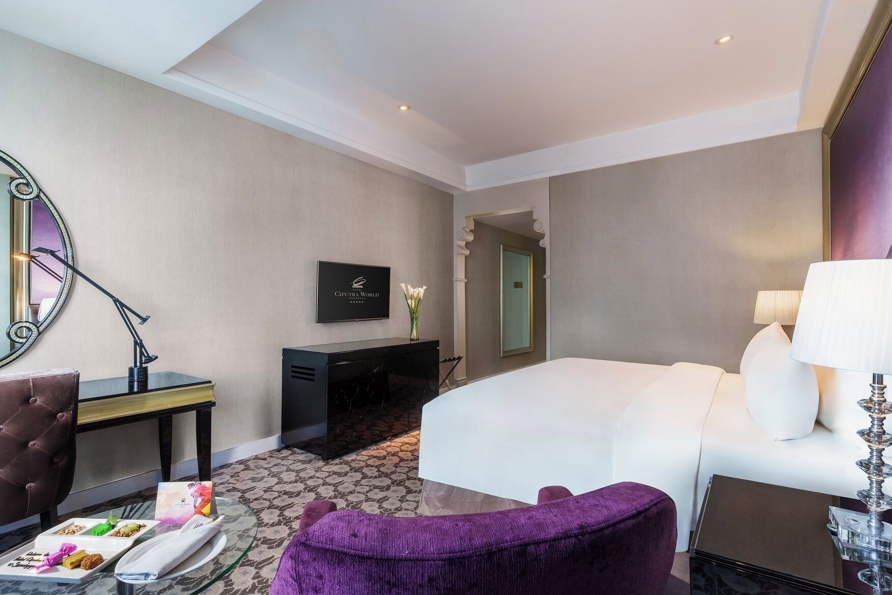 Une chambre d’hôtel avec un lit, un bureau avec une lampe, une chaise, une commode et un miroir.