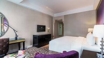 Une chambre d’hôtel avec un lit, un bureau avec une lampe, une chaise, une commode et un miroir.
