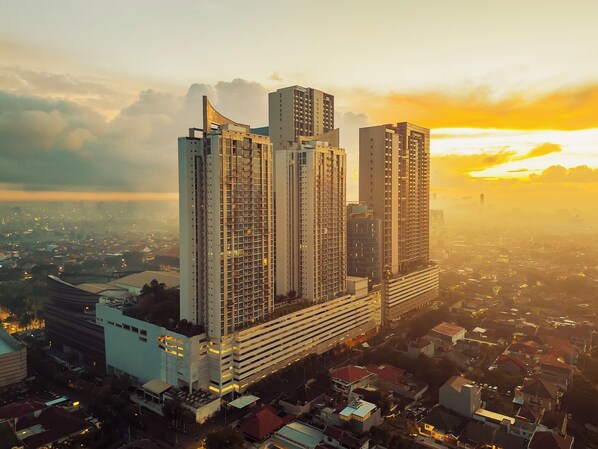 A high-rise building with multiple floors, surrounded by a cityscape during sunset.