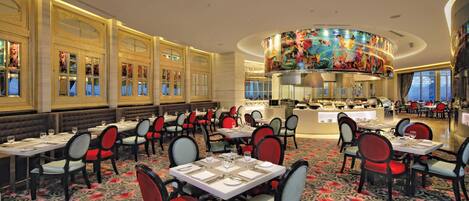 Un restaurante con varias mesas y sillas, una columna decorativa central y vista al área de comedor.