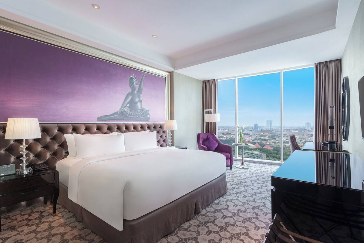 A spacious hotel room with a large bed, a view of the city, and a modern design.