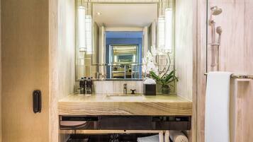 A modern bathroom with a large mirror, marble countertop, and a shower with a glass enclosure.