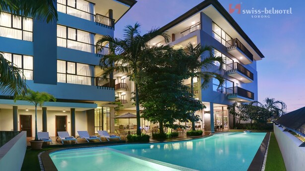 Ein modernes Hotel mit Schwimmbad, mehreren Balkonen und üppiger Bepflanzung.