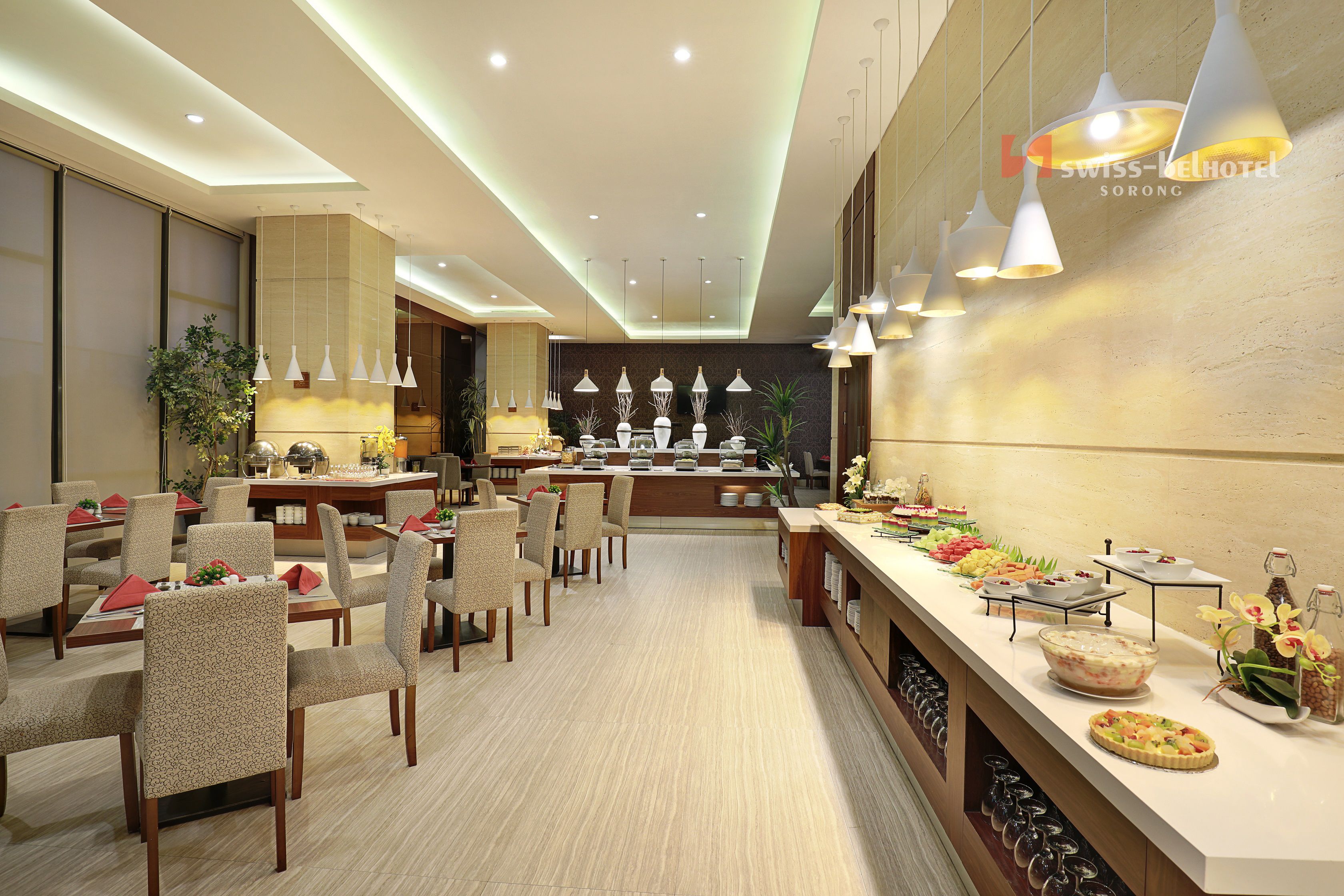 A hotel dining area with multiple tables, chairs, and a buffet with various food items.