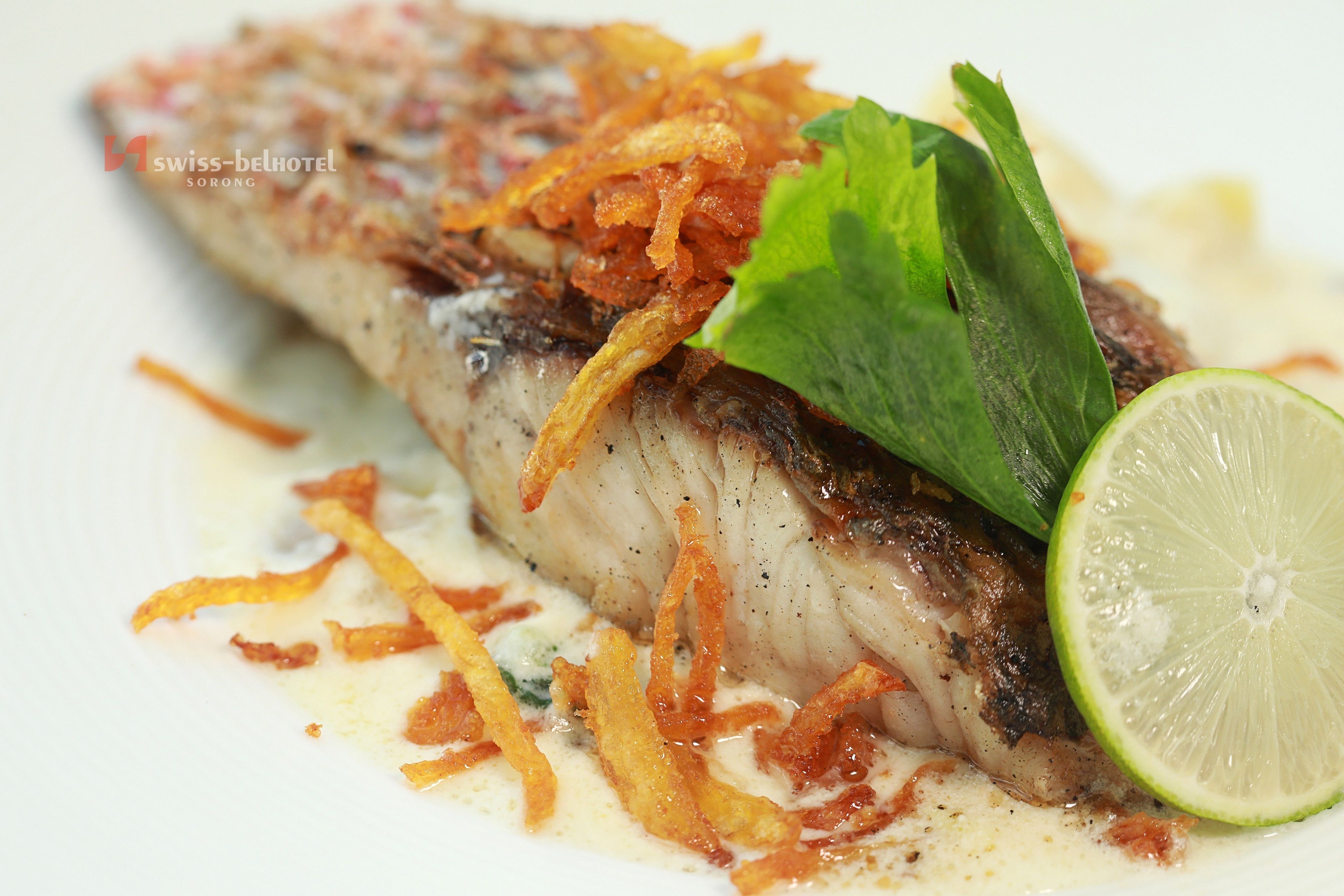 Un plato de pescado con guarnición crujiente y una rodaja de limón.