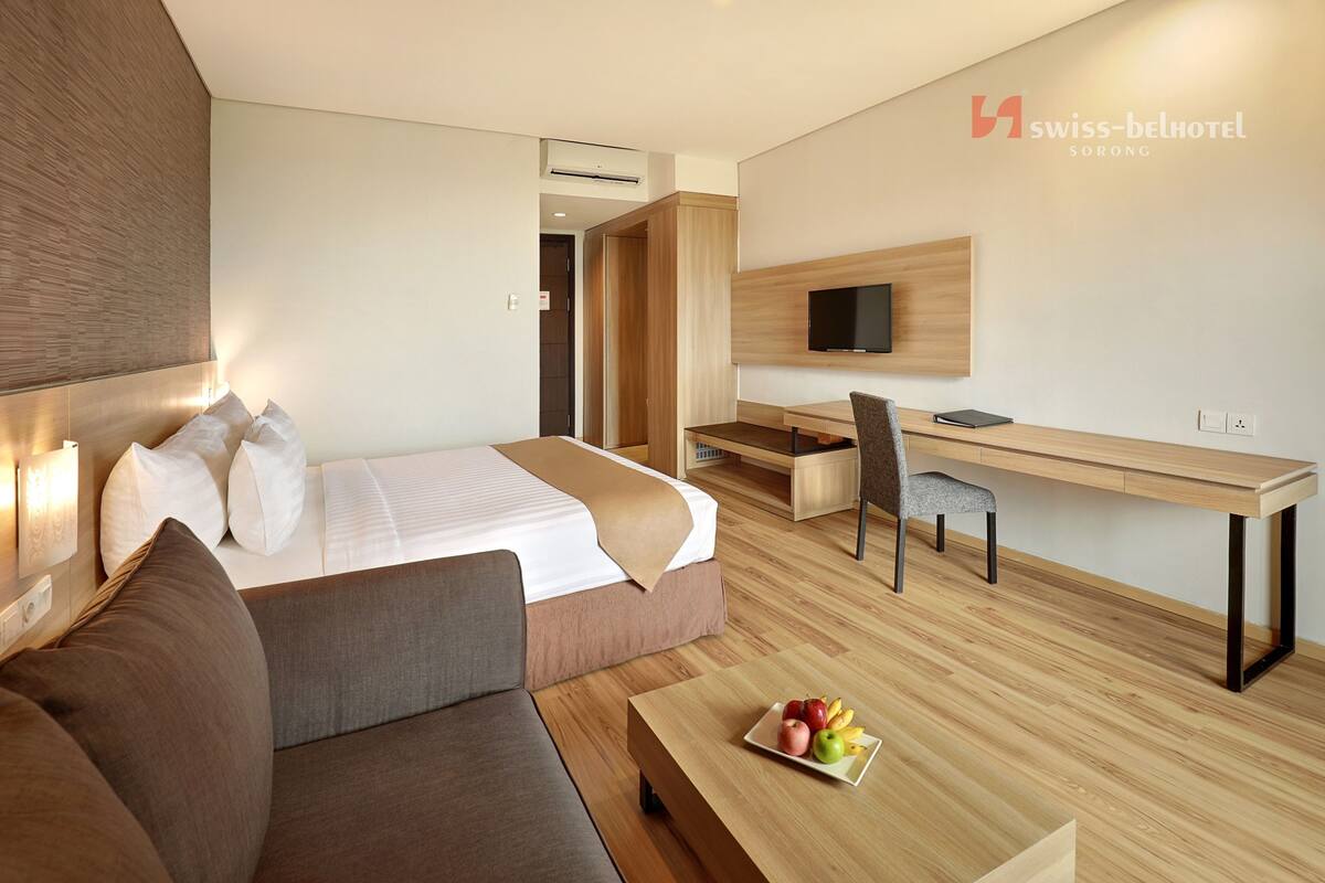 Una habitación de hotel moderna con cama, sofá, escritorio y televisor.