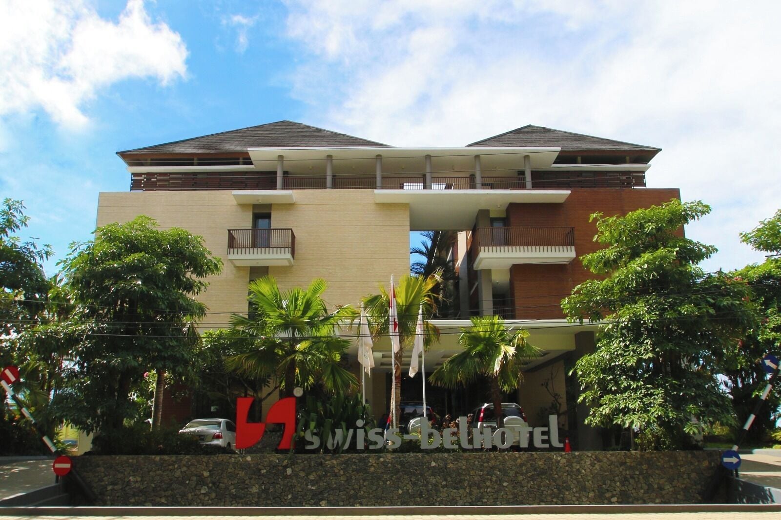 A hotel with a modern design, featuring a flat roof, balconies, and a sign for 'Swiss-bellhotel'.