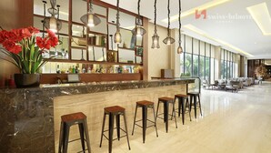 Eine Hotelhalle mit einem мрамор Reception Desk, mehreren Barhocker, hängenden Pendelleuchten und einem großen Spiegel.