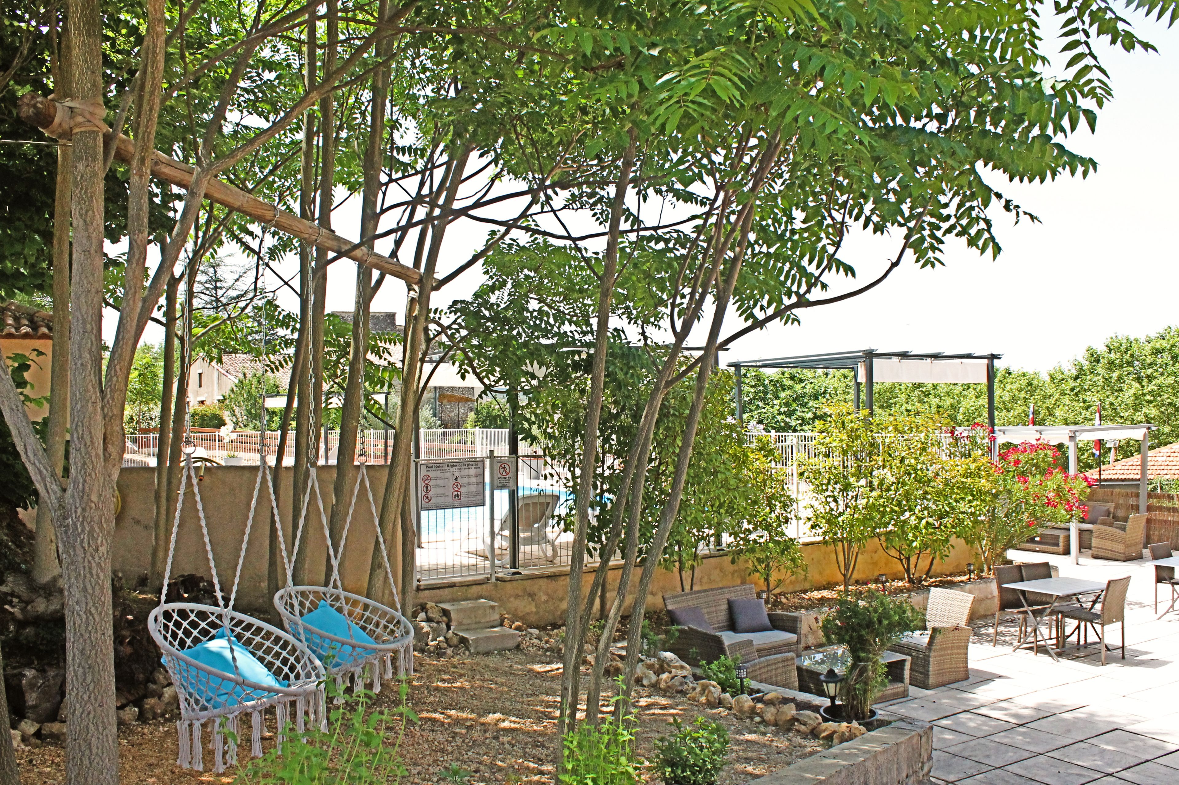 Un patio con mobiliario exterior, incluyendo una silla colgante y una mesa con sillas.