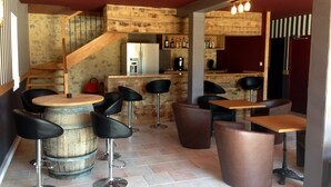 A bar area with stools and tables, a wooden counter, and a staircase. - Mont Bouquet Lodge (Brouzet-les-Ales)
