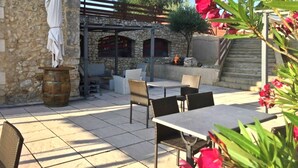 An outdoor patio area with stone walls, a statue, and outdoor furniture. - Mont Bouquet Lodge (Brouzet-les-Ales)