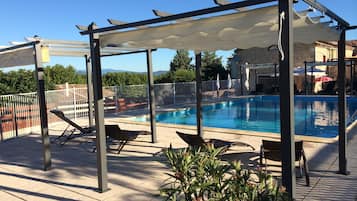 Una piscina al aire libre, sillones reclinables de piscina