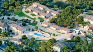 An aerial view of a residential area with multiple houses, a swimming pool, and surrounding greenery. - Mont Bouquet Lodge (Brouzet-les-Ales)