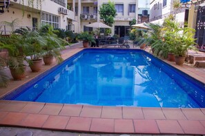 A rectangular pool with tiled edges, surrounded by potted plants and outdoor furniture. - Nne-eka Residence and Spa (Lagos)