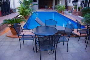 A poolside area with a round table and chairs, surrounded by potted plants. - Nne-eka Residence and Spa (Lagos)