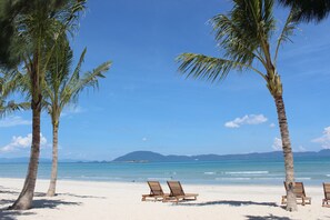 Playa privada, arena blanca, sillas reclinables de playa, sombrillas