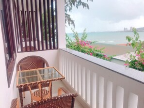 Enjoy breathtaking views of the sea from this balcony, featuring a glass table and two comfortable chairs.