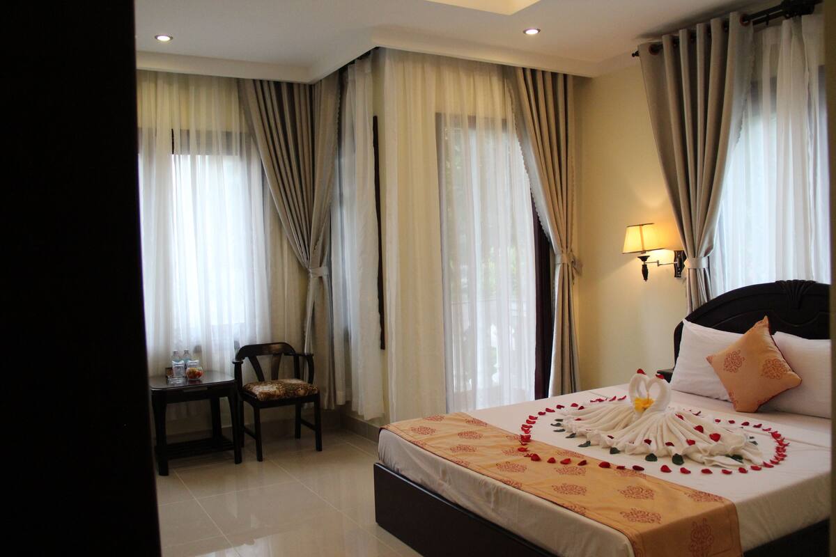 Une chambre d’hôtel avec un lit, une chaise, une petite table et une lampe.