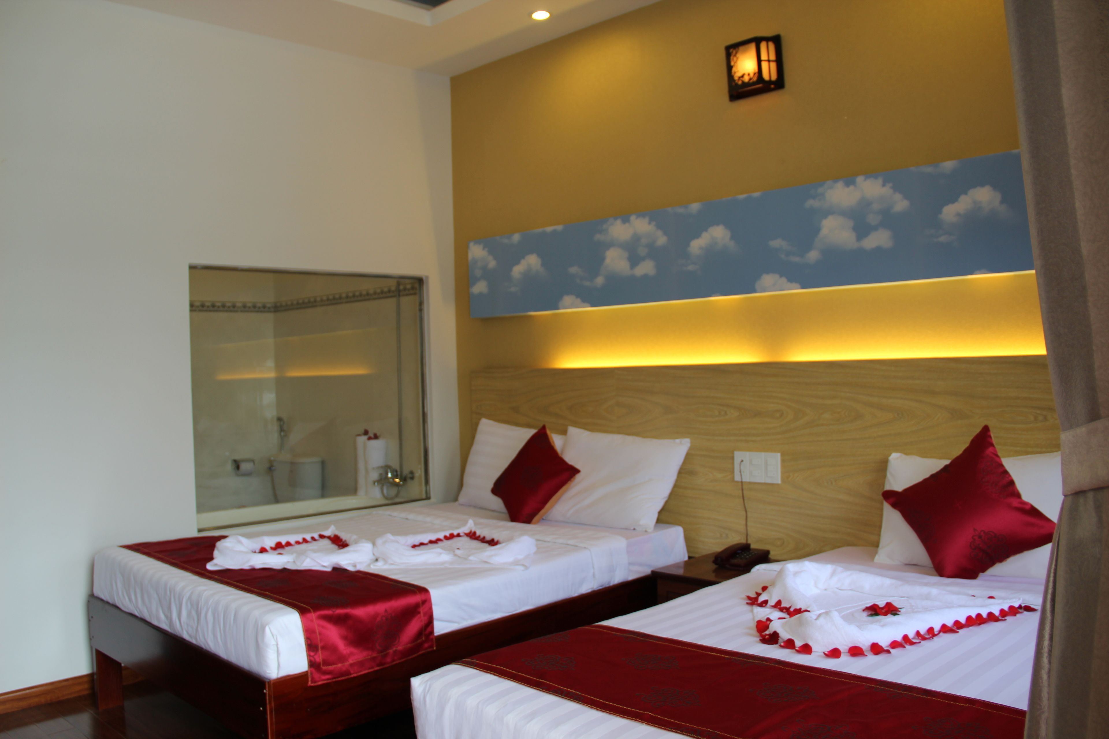 A hotel room with two beds, a large mirror, and a wall mural.