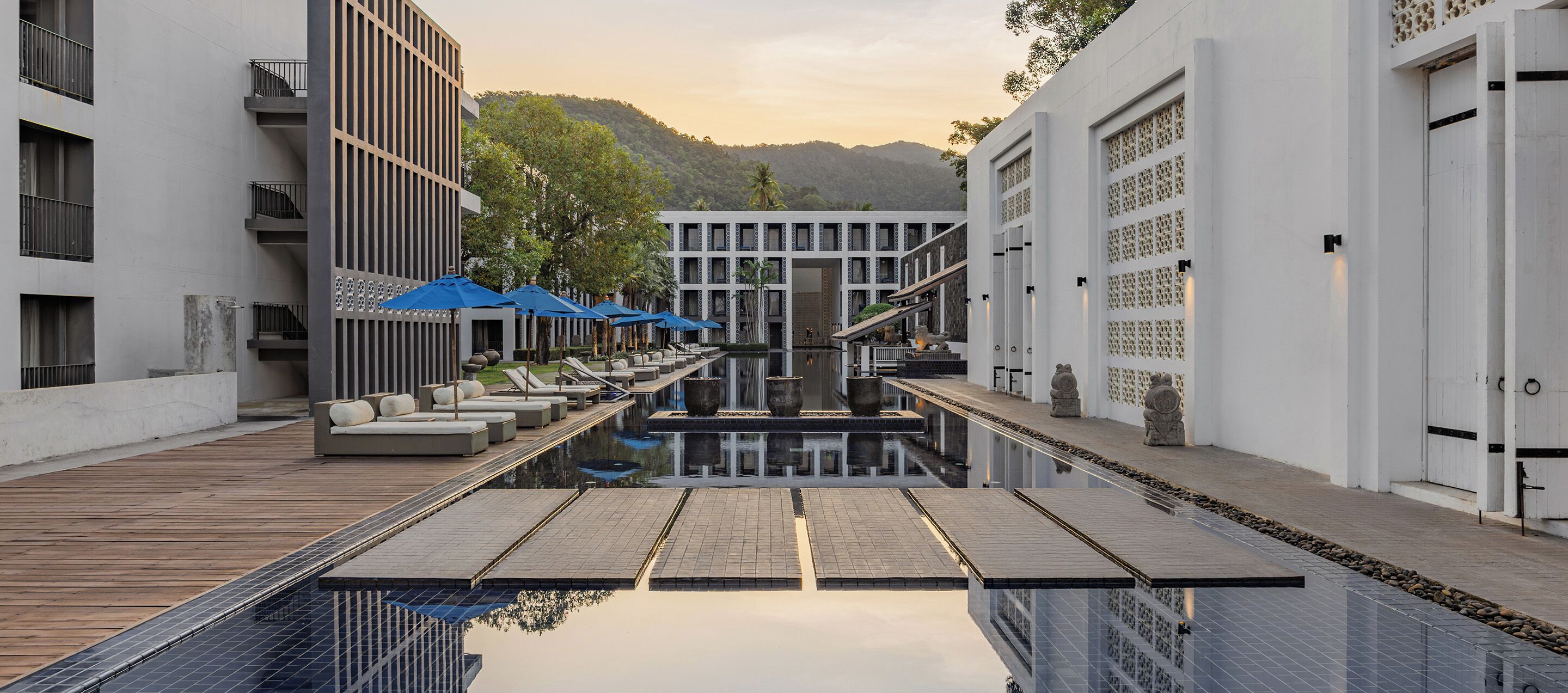 Een modern hotel met een zwembad, ligbedden en uitzicht op de bergen.