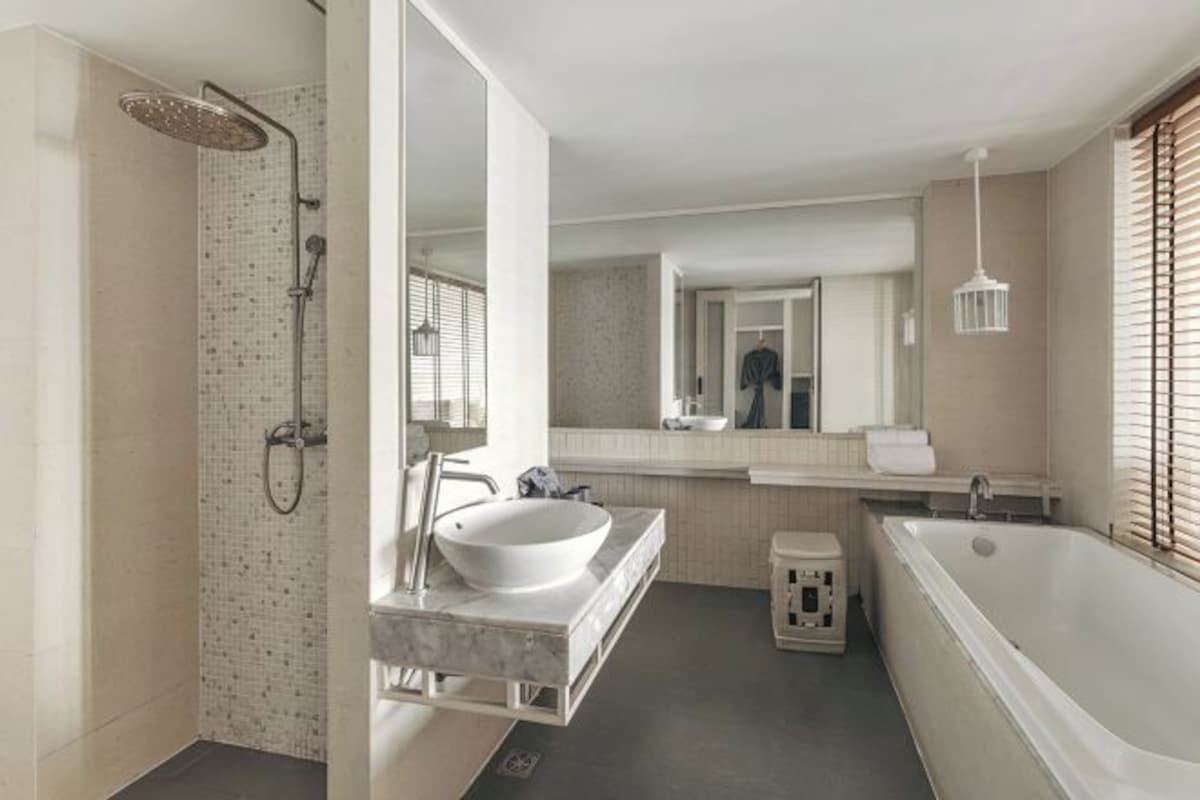 Un baño moderno con cabina de ducha a ras de suelo, una bañera amplia y un tocador con lavabo y espejo.