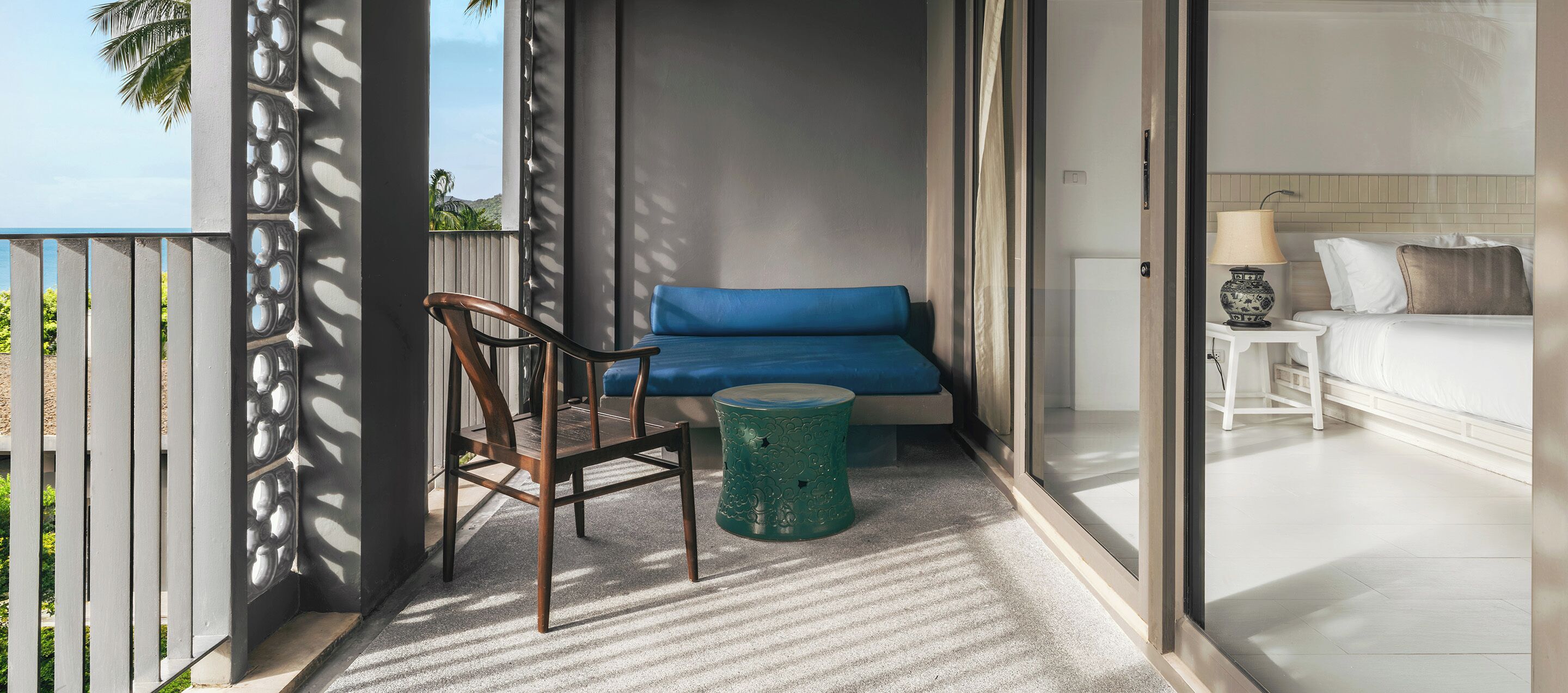 Ein Balkon mit einem Sessel, einem blauen Sofa und einem kleinen Tisch.