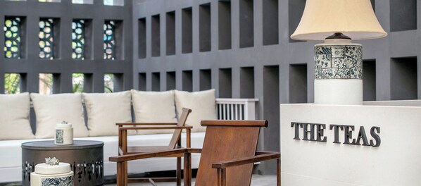 A modern interior with a sofa, chairs, a lamp, and a sign reading "THE TEAS". - AWA Koh Chang (Ko Chang)